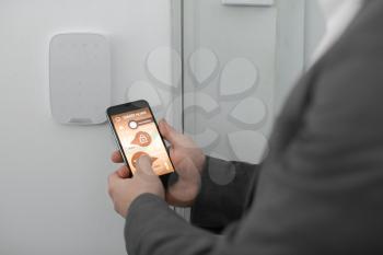 Man with mobile phone using smart home security system application�