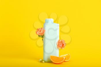 Shower gel, orange slices and flowers on color background�