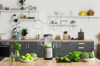Blender with healthy smoothie and ingredients on table in kitchen�