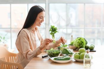 Young woman with fresh vegetables in kitchen�