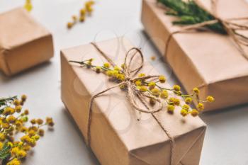 Gift boxes with mimosa branches on light background, closeup�