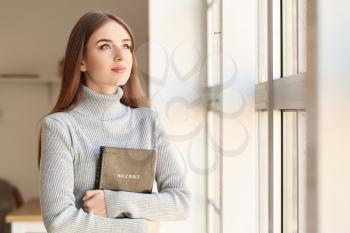 Young woman with Bible at home�