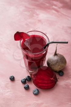 Glass of healthy smoothie with beetroots and blueberries on color background�