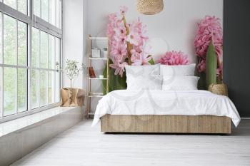 Stylish interior of bedroom with beautiful hyacinth flowers on wall�