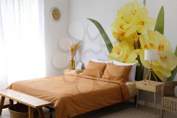 Stylish interior of bedroom with beautiful narcissus flowers on wall�