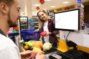 Young woman paying for goods in supermarket�