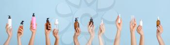 Many female hands with different cosmetic products on color background�