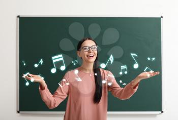 Beautiful music teacher near blackboard in classroom�