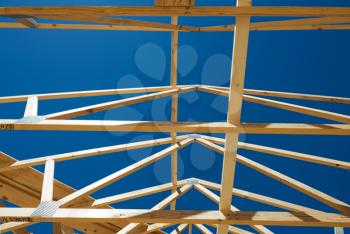 New residential construction home framing against a blue sky.