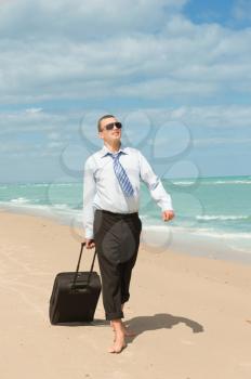 Businessman walking on the beach the first day of vacation