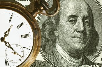 Time and Money concept image.
us currency and a pocket watch portray time and money.Business concept.
