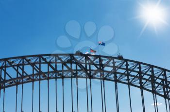 
middle part  of the Sydney Harbour Bridge with climbers and flags