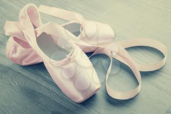 new pink ballet pointe shoes on  wooden background in vintage style