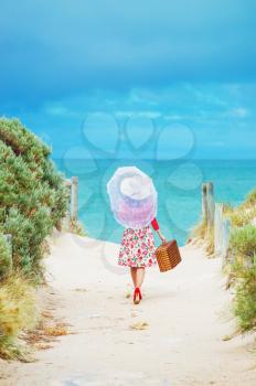 Beautiful woman traveler in retro style dress  on the beach. Local focus on the woman