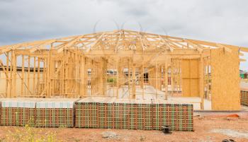 New residential construction home framing against a cloudy sky