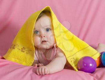 Adorable happy baby girl with yellow  towel on pink background 