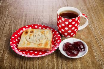 toasted bread with love message and raspberry jam and tea  .Breakfast for a loved one