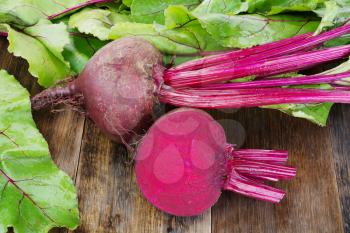  Fresh beetroots with leaves on wooden rustic table.Whole and cut  beetroots 