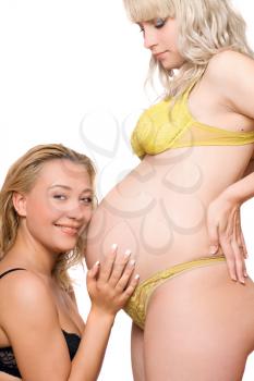 Royalty Free Photo of a Pregnant Woman With Another Women Looking at Her Belly