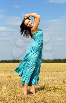 Royalty Free Photo of a Smiling Woman in a Blue Dress Standing in a Field