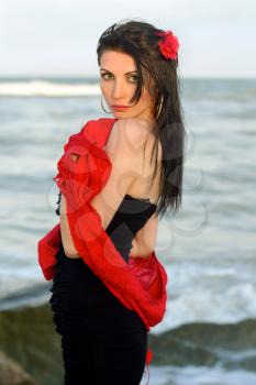 Portrait of charming young brunette in black dress on the beach