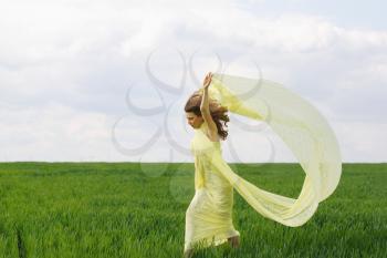 Attractive girl dancing in a green field
