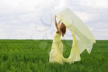 Charming girl dancing in a green field