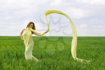 Charming young woman dancing in a green field