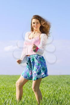 Playful pretty young woman in a green field