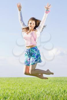 Cheerful beautiful young woman in a green field