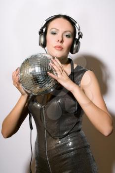 Portrait of attractive young woman in headphones with a mirror ball