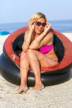 Joyful girl sitting in an inflatable chair on the beach