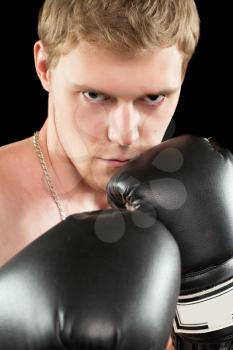 Young man in boxing gloves. Isolated on black