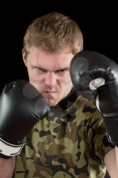 Portrait of furious young man in boxing gloves. Isolated