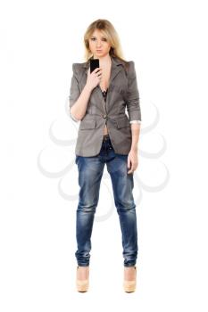 Beautiful young woman wearing grey jacket and blue jeans with a mobile phone. Isolated on white