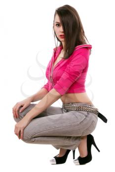 Mysterious brunette posing in short pink jacket and grey jeans. Isolated on white