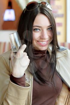 Portrait of young smiling brunette holding a glass of champagne. Isolated on white