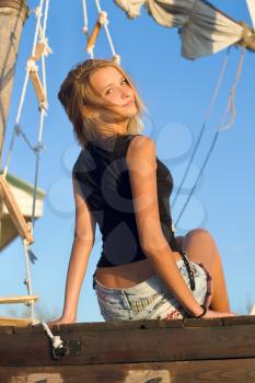 Nice teen girl sitting at stern of the ship