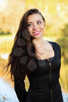 Cheerful young brunette posing in black dress