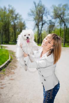 Smiling woman posing with a white dog in the park