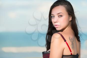 Portrait of sexy young woman with tattoo posing on the beach
