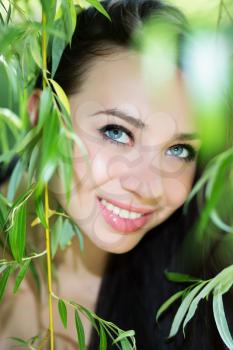 Smiling young brunette posing in the green branches