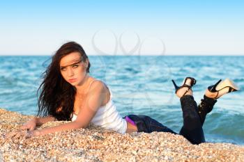 Pretty woman in white shirt and jeans lying on the beach