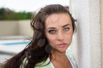 Portrait of pretty young brunette posing near the wall