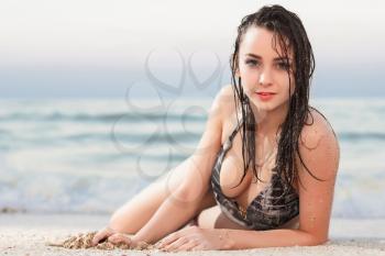 Attractive young woman in wet swimsuit posing near the sea
