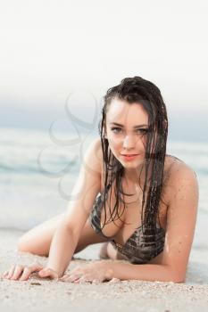 Young woman with wet hair lying near the sea