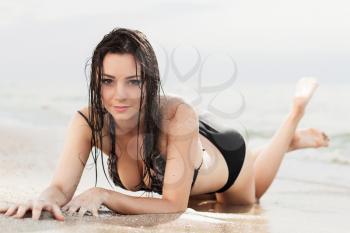 Attractive young woman posing in wet swimsuit on the beach