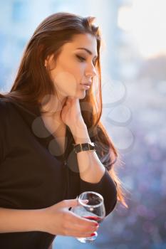 Portrait of thoughtful young woman with a glass of wine