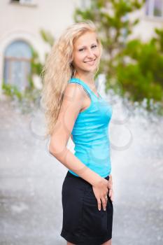 Pretty smiling blond woman posing near the fountain
