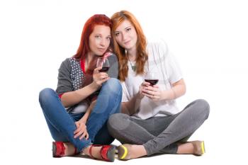 Two redhead women sitting cross-legged with glasses of wine. Isolated on white